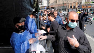 People queue in line to receive packages for precautions against coronavirus disease provided by the Basij, a militia loyal to Iran's Islamic republic establishment, from a booth outside Meydane Valiasr metro station in the capital Tehran. AFP