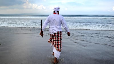 A Balinese man in a trance walks towards the water during a Melasti ceremony prayer at Petitenget beach near Denpasar, Indonesia. Sonny Tumbelaka / AFP Photo