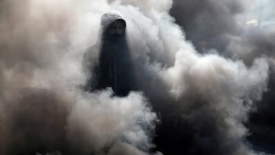 An Iraqi demonstrator walks among smoke from burning tires during ongoing anti-government protests in Kerbala, Iraq, January 20, 2020. Reuters