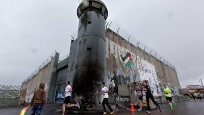 Participants in the Right to Movement Palestinian Marathon pass an Israeli guard tower and 'separation barrier,' as they run in Bethlehem.