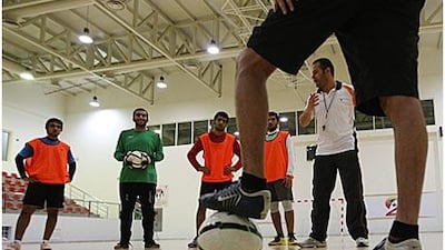 Coach Munsif al Sassi, in white shirt, briefs his players before the start of their training.