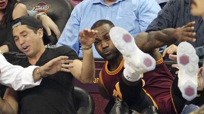 Cleveland Cavaliers’ LeBron James falls into Ellie Day, wife of PGA Tour golf player Jason Day, at left, during the second half of an NBA basketball game against the Oklahoma City Thunder in Cleveland. John Kuntz / The Plain Dealer via AP