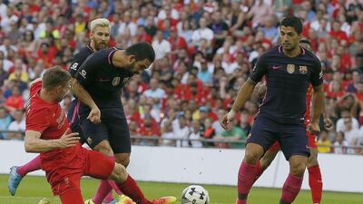 Barcelona midfielder Arda Turan, second left, is tackled by Liverpool’s James Milner. Frank Augstein / AP Photo