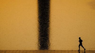 An early morning runner passes the shadow of the Washington Monument in the US capital. J David Ake / AP Photo