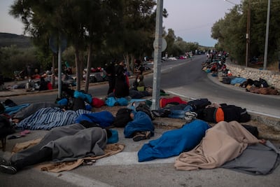 Refugees and migrants sleep on a street near the destroyed Moria camp after the fire in September 2020. AP