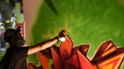 Abdullah Al Mahrouqi spraying yellow on to his canvas. Courtesy Ismael David