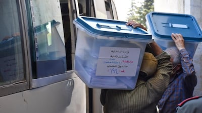 Syrian men carry ballot boxes on to a bus for delivery to polling stations on the eve of the parliamentary elections, in the Syrian city of Aleppo on July 18, 2020. AFP
