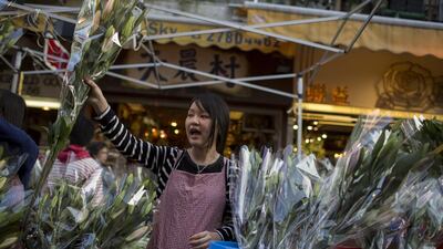 A vendor holds up lilies for sale at a flower market in the Mongkok district of Hong Kong. Brent Lewin / Bloomberg