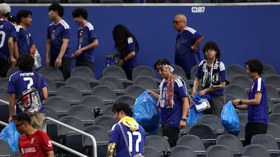 Japan fans clear trash from the stands at the Dallas Stadium. AFP