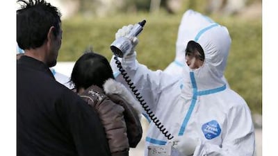 An official scans a man and a child for radiation at an emergency centre yesterday, in Koriyama, Japan.