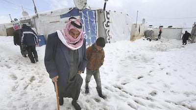 An old Syrian man helped by his grandson walks on the snow at their refugee camp in Al Faour village in Lebanon's Bekaa Valley on January 8. AP Photo