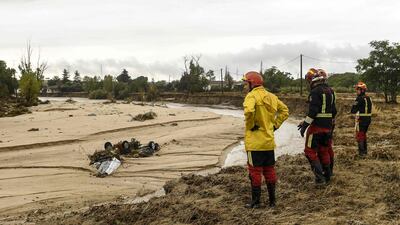 Firefighters look at cars stranded on a river bank in the town of Aldea del Fresno, Spain. AFP