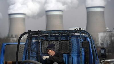 A worker throws his cigarette while smoking on a truck parked in front of a cooling towers of a coal-fired power plant in Datong, Shanxi province, China. AP Photo