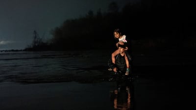 A man carries a young girl on his shoulders as he and a group of several hundred migrants wade across the Rio Grande into Eagle Pass, Texas, from Piedras Negras, Coahuila, Mexico. Reuters