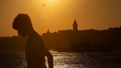 A boy walks near the Bosphorus against the backdrop of the Galata Tower at sunset in Istanbul, Turkey. EPA