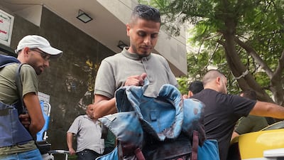 A man carries a blood-stained flak jacket belonging to a Palestinian journalist, who was killed with two colleagues when an Israeli missile hit a hospital building while they were outside reporting, in Gaza city. Reuters