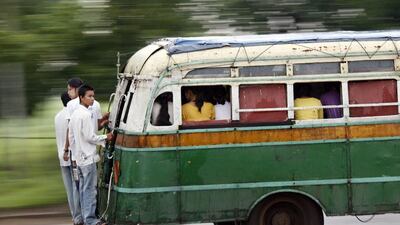 Men stand on the back of a bus while catching a ride on the road to Yangon. The city is undertaking a major reform of its creaking bus network. Soe Zeya Tun / Reuters