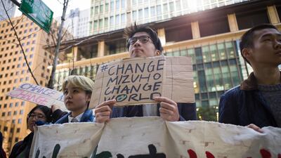 A group of youth climate activists from Fridays for Future Tokyo hold up a protest banner and placards outside Mizuho Financial Group's Tokyo headquarters. Bloomberg