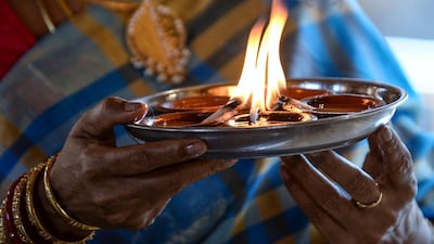 A Hindu devotee offers prayers while holding oil lamps or diyas during Diwali, the Hindu festival of lights, at a temple in Colombo on November 14, 2020. / AFP / LAKRUWAN WANNIARACHCHI