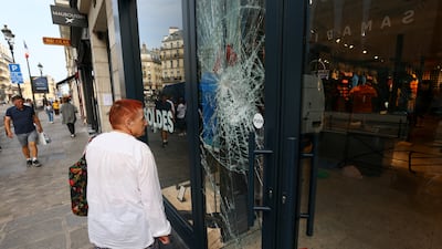 A woman looks at the damaged windows of a Jott store on Rue de Rivoli. Reuters