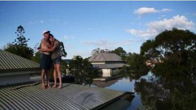 A man comforts his daughter on their roof in the town of Bundaberg as parts of southern Queensland experiences record flooding in the wake of ex-tropical Cyclone Oswald.
