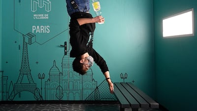 An employee of the Museum of Illusion disinfects a bench after the passage of visitors. AFP