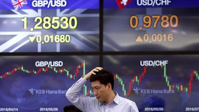 A currency trader walks by the screens showing the foreign exchange rates at the foreign exchange dealing room in Seoul, South Korea, on Wednesday, July 6, 2016. Lee Jin-man / AP Photo