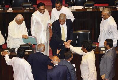 Sri Lanka's members of parliament shake hands with ousted prime minister Ranil Wickremesinghe during a parliament session in Colombo. AFP
