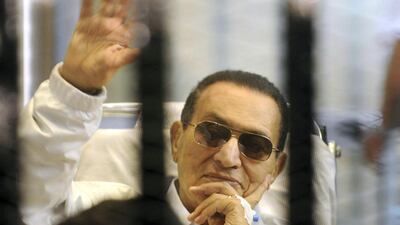 Former Egyptian president Hosni Mubarak waves to his supporters from behind bars as he attends a hearing in his retrial on appeal in Cairo, in 2013. AP Photo