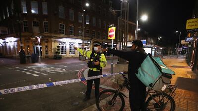 A police officer gestures next to a delivery rider at the scene of reported multiple stabbings in Reading. REUTERS