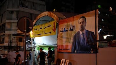 Supporters of Lebanese Prime Minister Saad Hariri stand next of his portrait with Arabic words that read, "God with you," in Beirut, Lebanon. AP Photo