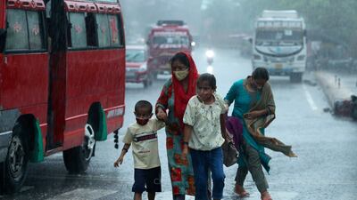 A family is soaked by the downpour in Jammu, India.