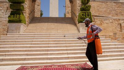 A worker spays disinfectant before the start of Friday prayer in Amman, Jordan. EPA