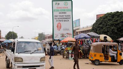 People walk past an Internal Revenue Service signboard along a dusty road in the Bata district in Nigeria's northern city of Kano August 25, 2017. REUTERS/Akintunde Akinleye
