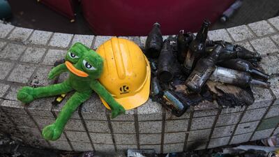 A stuffed toy depicting Pepe the Frog, a character used by pro-democracy activists as a symbol of their struggle, is seen next to a helmet and burnt glass bottles. AFP