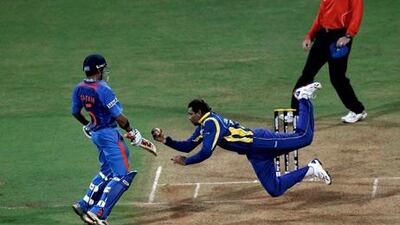Tillakaratne Dilshan of Sri Lanka dives to take a catch off his own bowling to dismiss Virat Kohli of India.