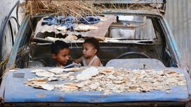 Palestinian children sit in the wreckage of a car in the Bureij refugee camp in the central Gaza Strip. AFP