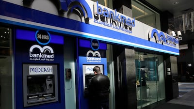 A man uses the ATM outside a bank, in Beirut, Lebanon. AP