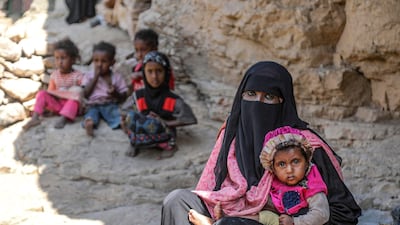 A woman holds a child as she sits near other children outside a cave where a Yemeni family has sought refuge due to poverty and lack of housing, west of the suburbs of Yemen's city of Taez. AFP