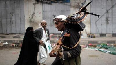 Passers-by look on as an armed tribesman loyal to tribal leader Sadiq al Ahmar mans a checkpoint near Sheikh al Ahmar's house in Sana'a yesterday.