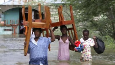 People salvage items during flooding from Tropical Storm Hanna, in L'Artibonite, northern Haiti.