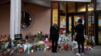 People look at tributea to slain teacher Samuel Paty at the entrance of a middle school in Conflans-Sainte-Honorine, 30km north-west of Paris, on October 17, 2020, a day after he was attacked and decapitated. AFP