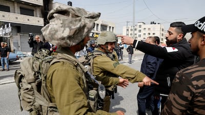 An Israeli soldiers speak to a Palestinianians near in the West Bank town of Hawara. Reuters