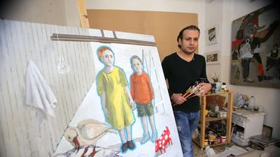 Iraqi refugee artist Saddam Al Jumaily stands next to his painting of he and his sister in Amman, Jordan. (Salah Malkawi for The National)