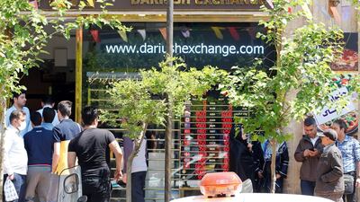 Iranians check the currency rate around an exchanges shop in Tehran. ABEDIN TAHERKENAREH/EPA