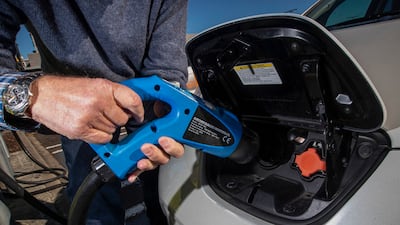 A driver charges his electric vehicle at a station. AP