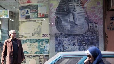 A woman, right, uses her mobile phone as she passes a currency exchange store in Cairo. Shawn Baldwin / Bloomberg