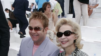 Elton John, in a lilac suit and pink T-shirt, and Lyne Wyatt attend the Chanel haute couture autumn/winter 2006/07 show during Paris Fashion Week on July 6, 2006. Getty Images