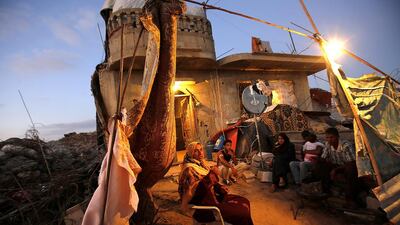 Adnan Al Najar, 53, and his family await the end of the day’s fast at their house in Khan Younis, southern Gaza. Their home was wrecked in Israel’s 50-day assault a year ago. The truce ending the war has held but few root causes have been addressed. Report, a9. Mohammed Saber / EPA