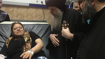 Egypt's Coptic priest Agathon, centre, speaks to a woman who was wounded after gunmen attacked a bus. AFP
